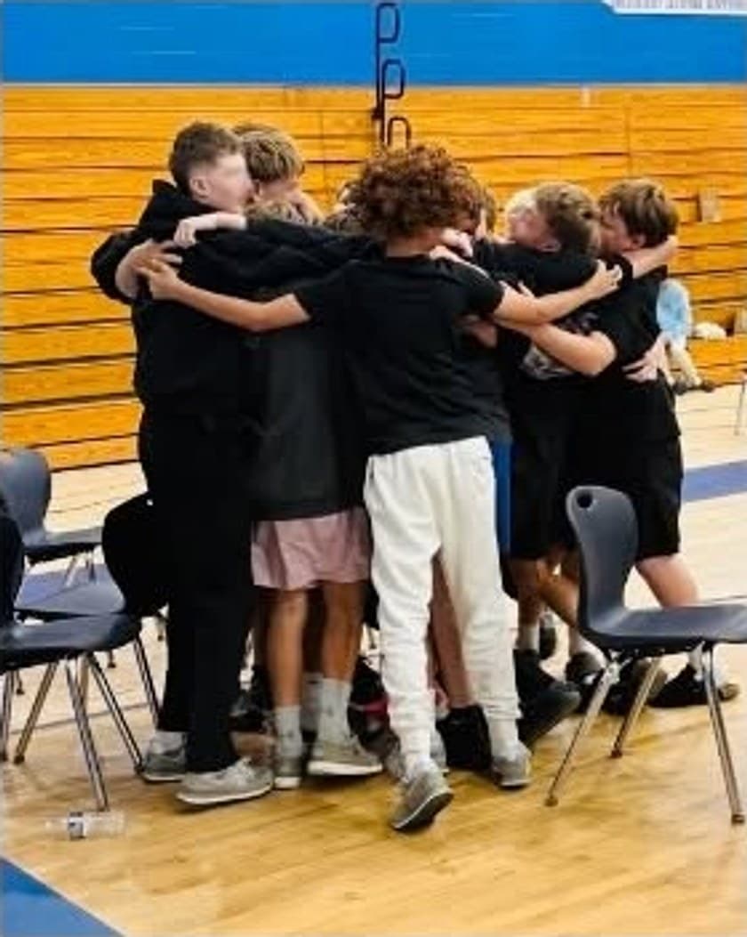 A group of students with their arms around each other in a school gym